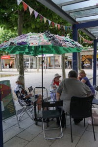 Eine Gruppe von Menschen sitzt unter einem Sonnenschirm an einem Tisch