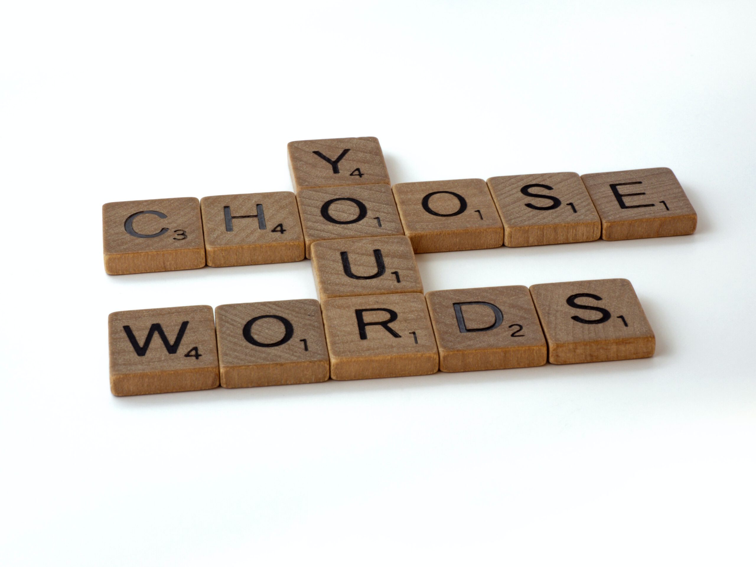 Aus Holz bestehendes Puzzleteile auf dem Buchstaben zu sehen sind. "Choose Your Words" ist auf dem Bild mit den Puzzleteilen zu lesen.